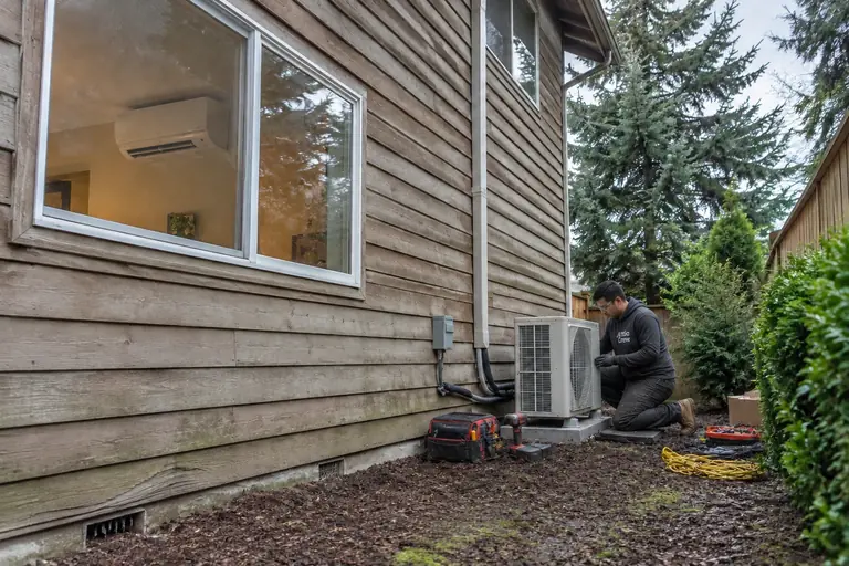 Ductless heat pump installed on a two-story home, in progress: Installation continues with final line set insulation, system testing by the technician, and preparation for sealing indoor components.