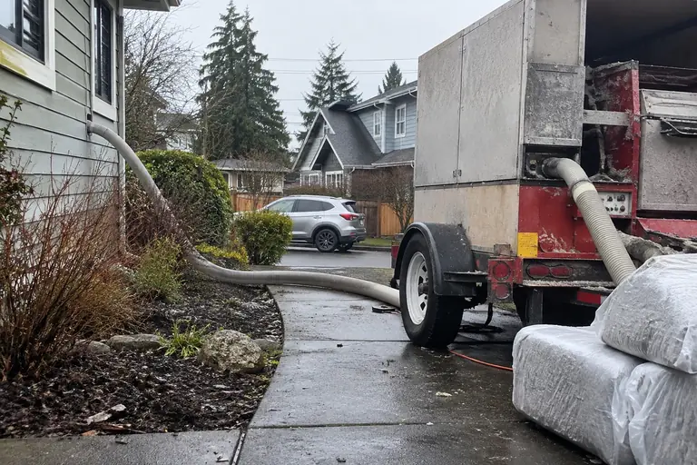 A dense-pack cellulose machine and hose at the curb.