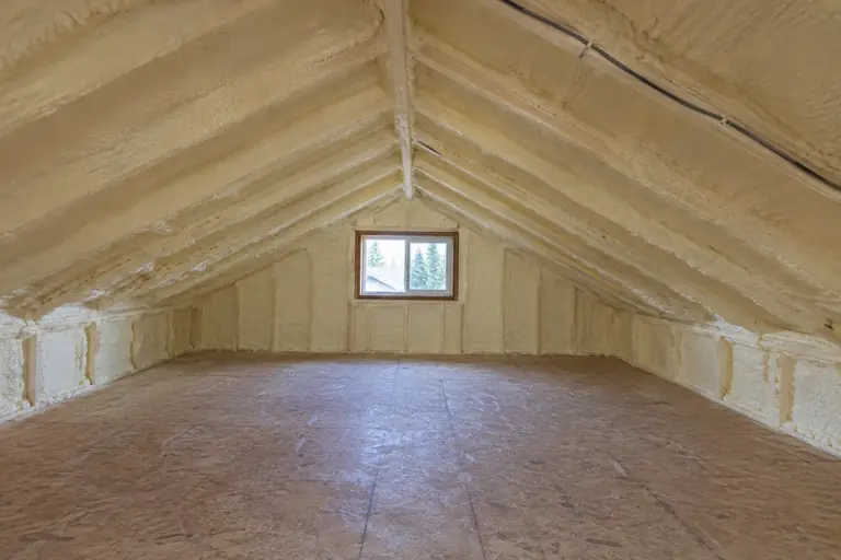 Attic spray foam insulation replacement in mid-century rambler attic, after: With insulation replacement complete, the attic cavity is fully sealed and insulated with closed-cell spray foam.