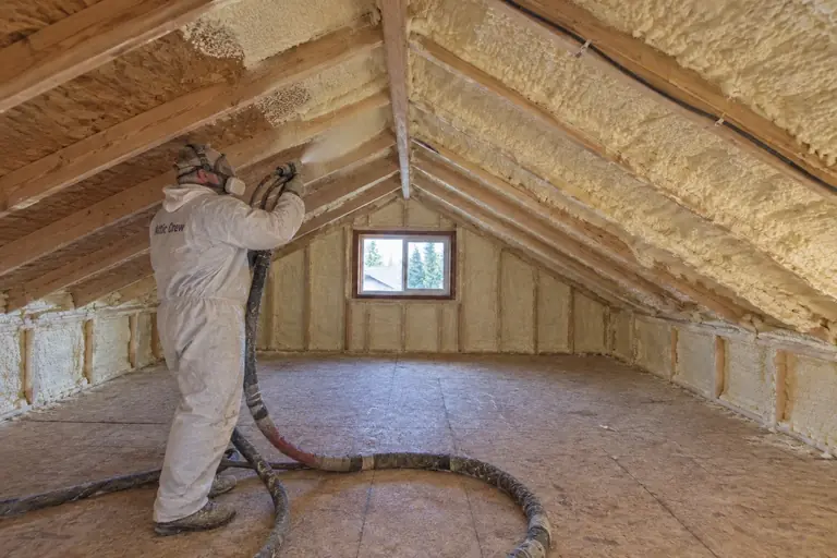 Attic spray foam insulation replacement in mid-century rambler attic, in progress: During installation, the technician applies closed-cell spray foam to seal and insulate the attic roof deck and rim joists.