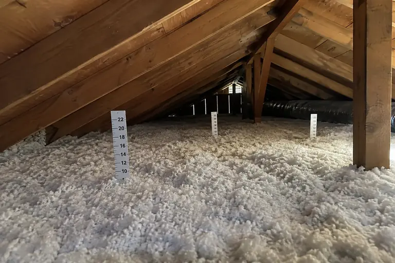 Close-up of finished blown-in attic insulation with depth markers.