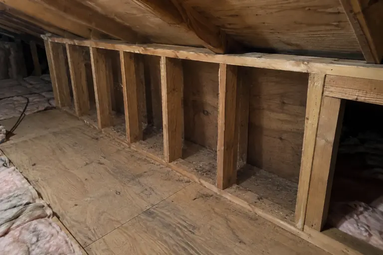Insulating an uninsulated knee wall, before: The knee wall cavities are completely open with no insulation, exposing the framing and allowing drafts.