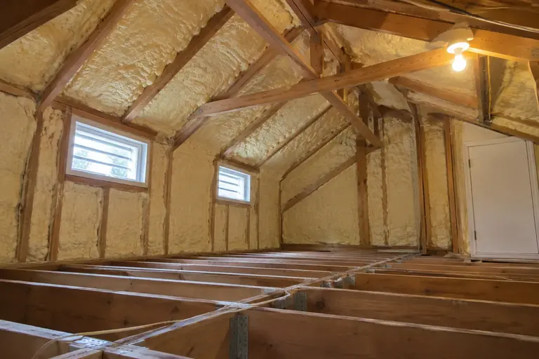 Spray foam attic insulation replacement in 1990s split-level home attic, after: The attic is clean and fully insulated with closed-cell spray foam, offering superior sealing and improved home comfort.